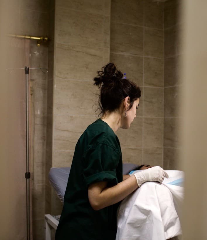 Cathy aan het werk in de zorg, bij een patiënt in een ziekenhuiskamer